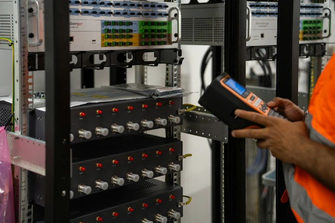 Technician inspecting server racks with a handheld diagnostic tool